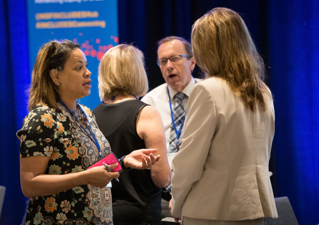 A photo of professionals speaking with each other at a conference. 