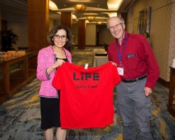 Two adults hold up a t-shirt reading "LiFE".