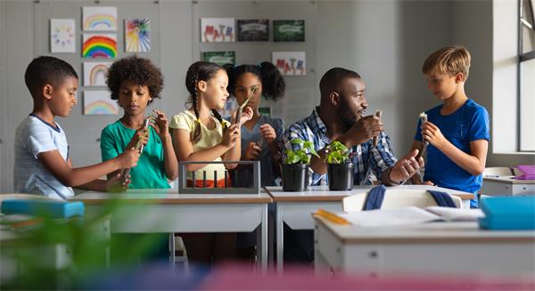 A group of students work a teacher in a science classroom. 