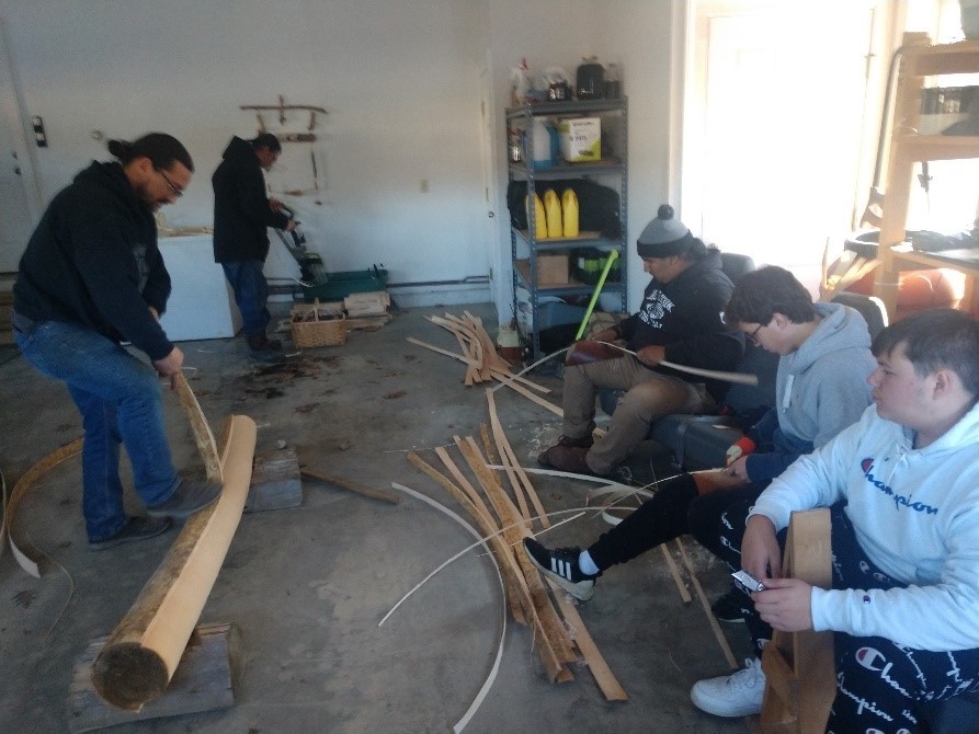 A group of young adults work with wood and bark. 