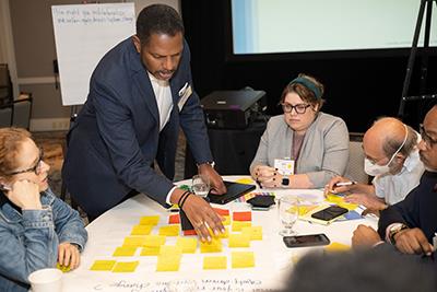 Professionals discuss using sticky notes during a conference. 