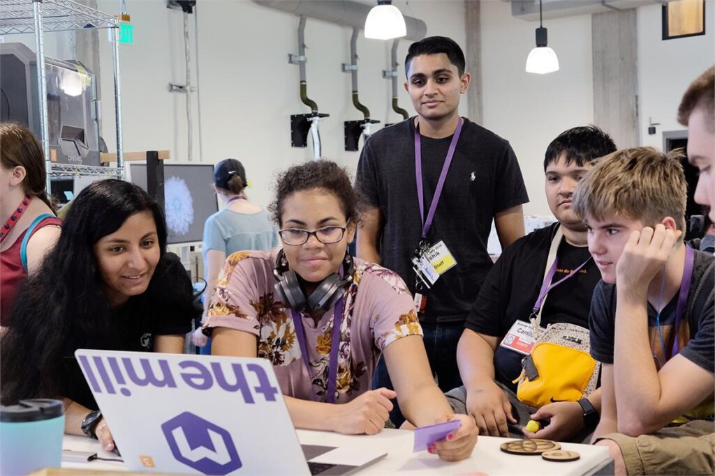 A group of students look at a computer. 