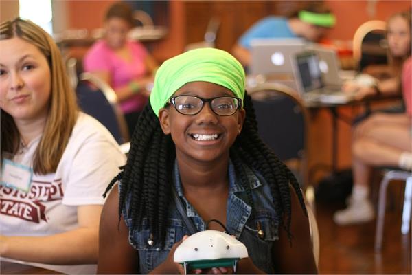 A young woman poses for a photo with an electronic device. 